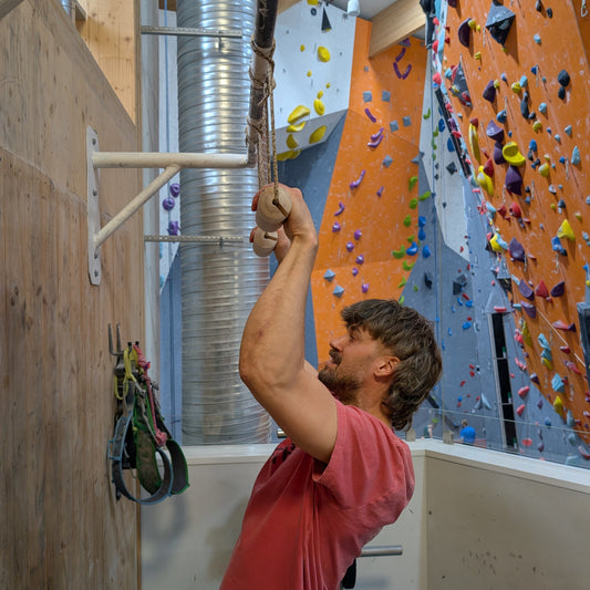 Climber performing pull-ups and hangs using two FIKA Rulltårta handles attached to a pull-up bar.