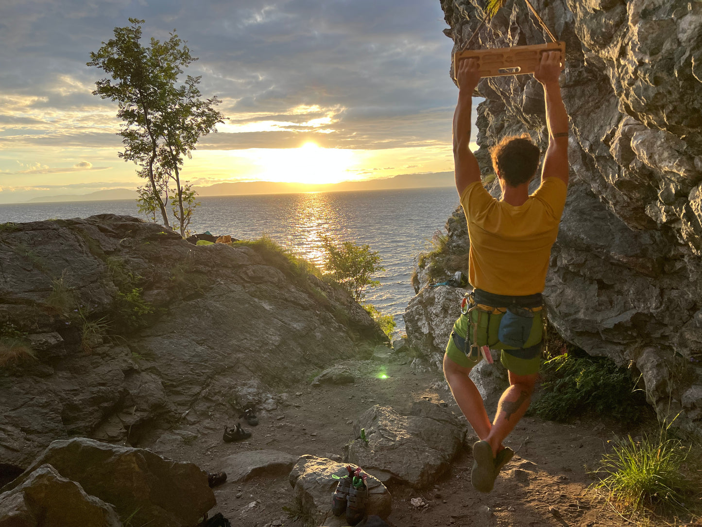 Training on the FIKA Vetelängd portable hangboard at a coastal cliff during sunset.