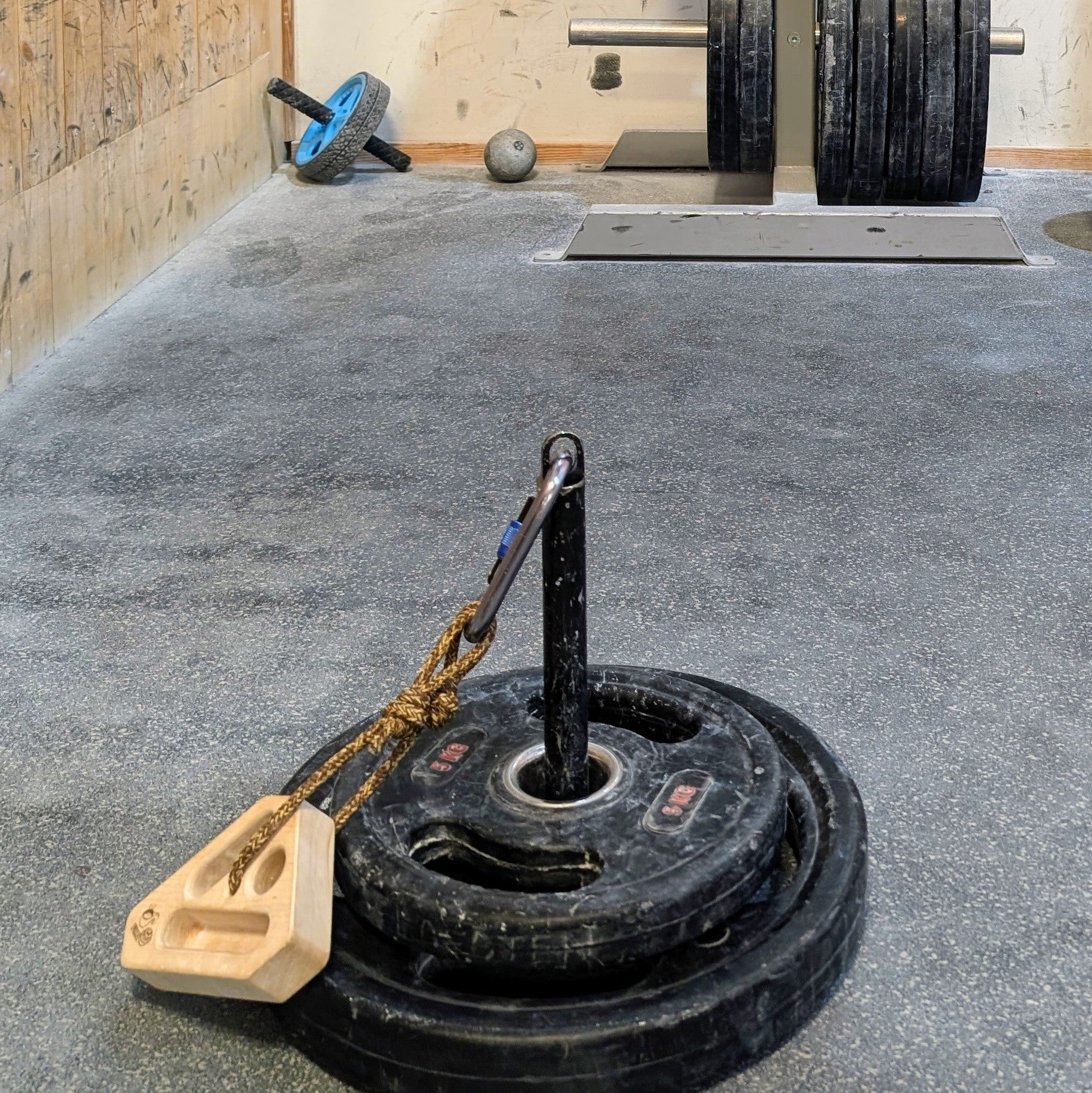 FIKA Rullrån steel loading pin with weights attached to a wooden grip block.